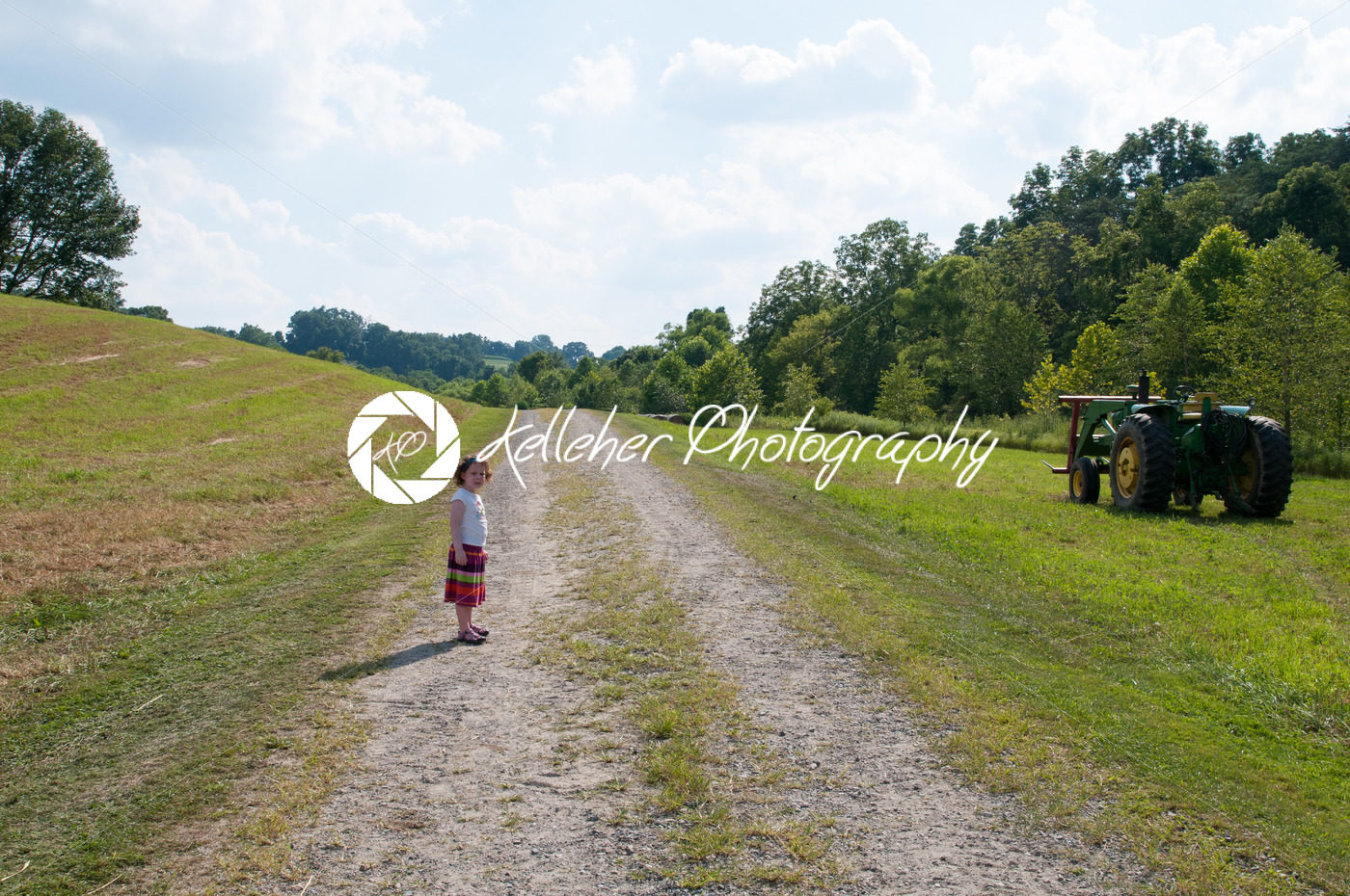 Girl on dirt pathway surrounded by green open space with mature trees on a sunny day with light clouds at Stroud Preserve - Kelleher Photography Store
