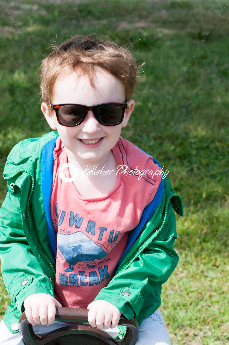 Happy little boy is swinging on see-saw wearing oversized sunglasses - Kelleher Photography Store