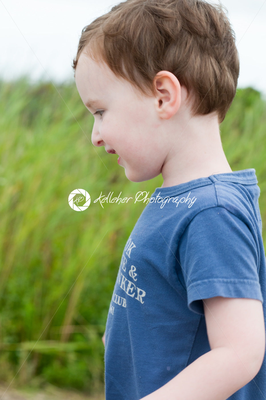 Profile of young boy walking outside along beach sand dunes with reeds - Kelleher Photography Store