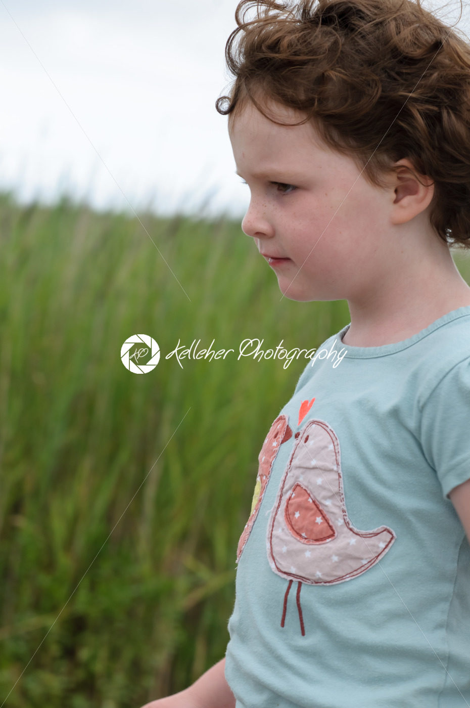 Profile of young girl walking outside along beach sand dunes with reeds - Kelleher Photography Store