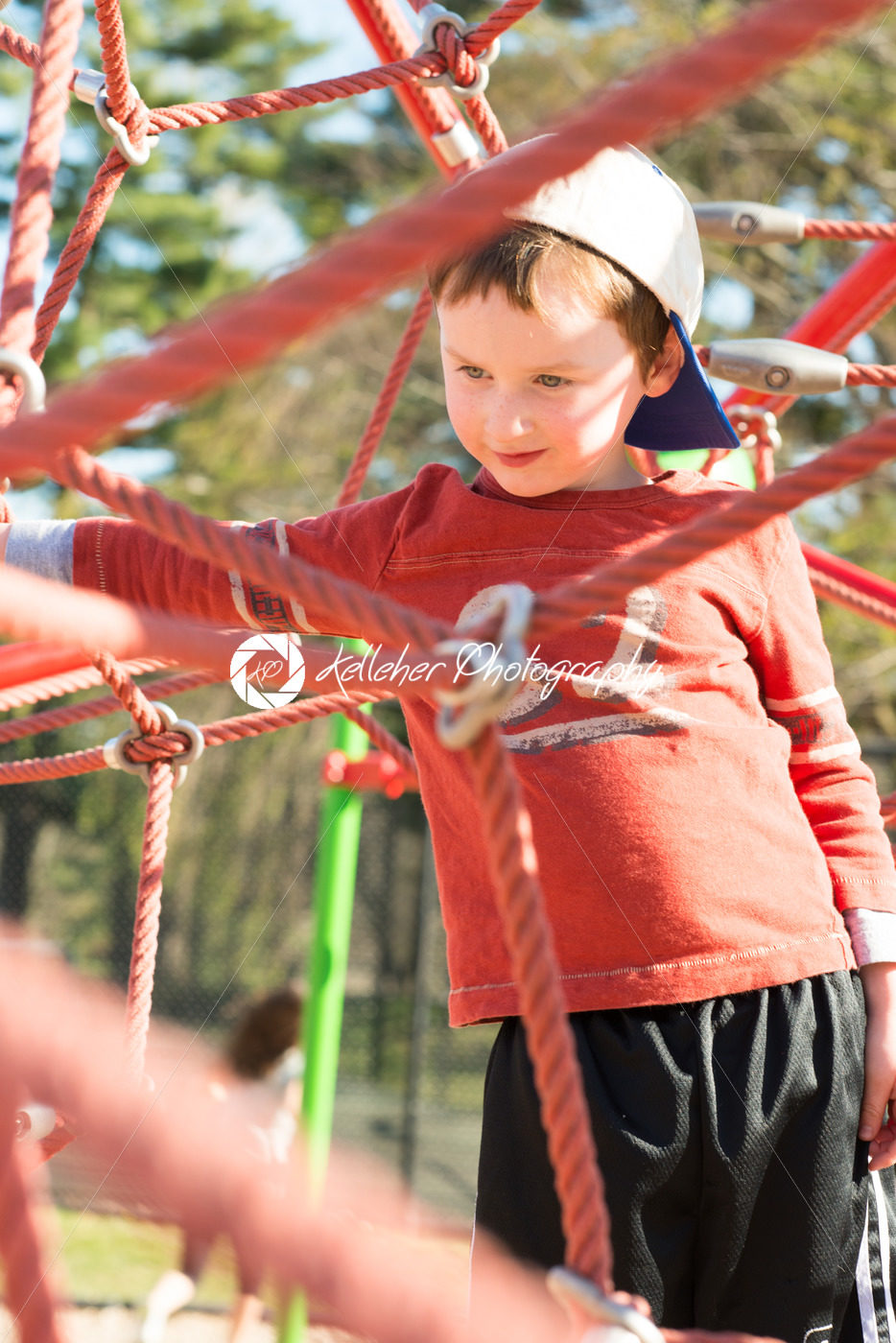 Young boy child playing at outdoor playground climbing net - Kelleher Photography Store