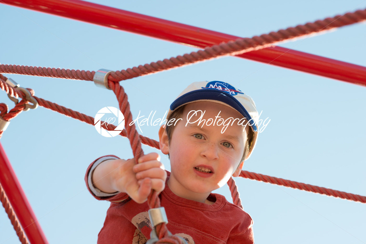 Young boy child playing at outdoor playground climbing net - Kelleher Photography Store