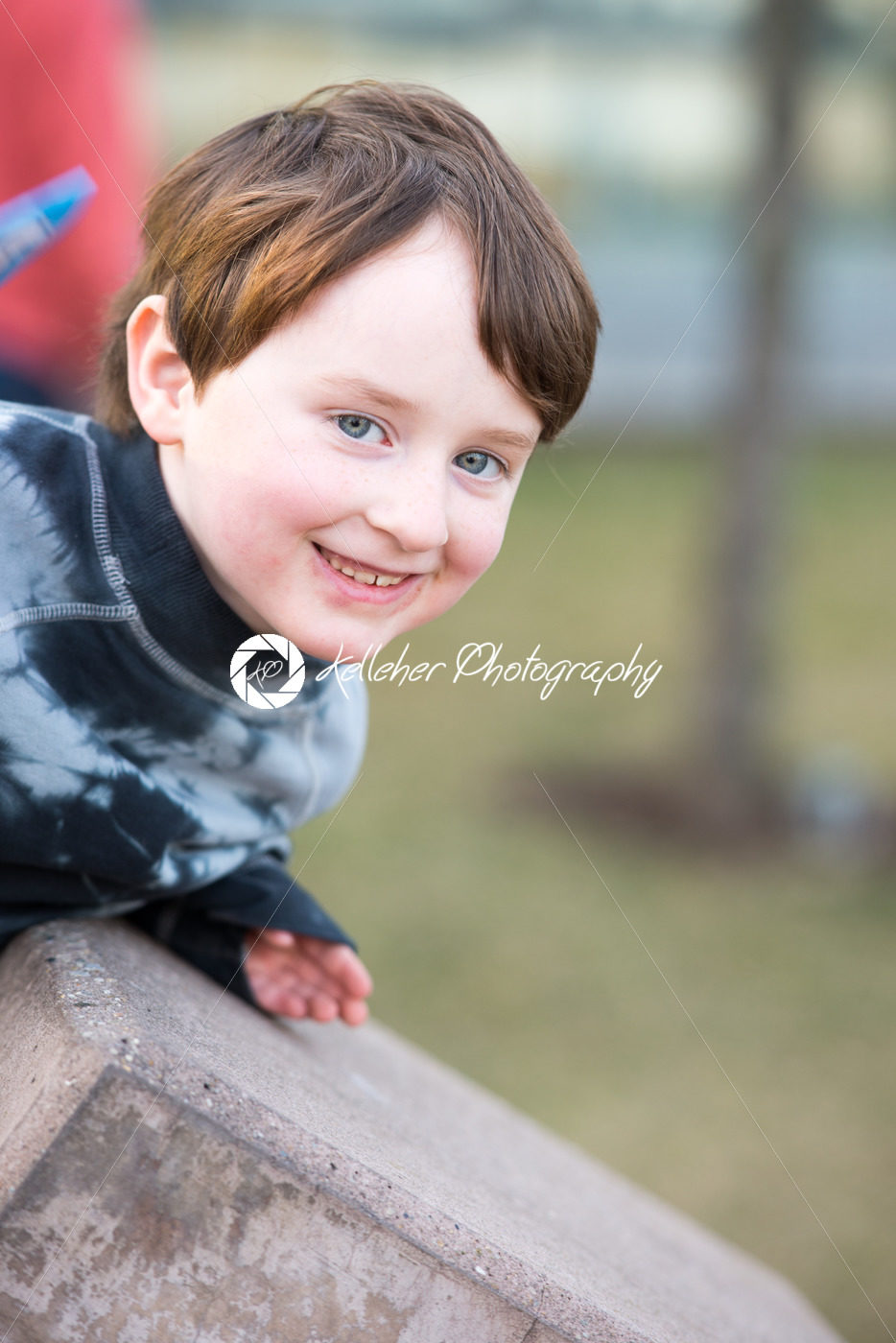 Young boy leaning over looking and smiling - Kelleher Photography Store