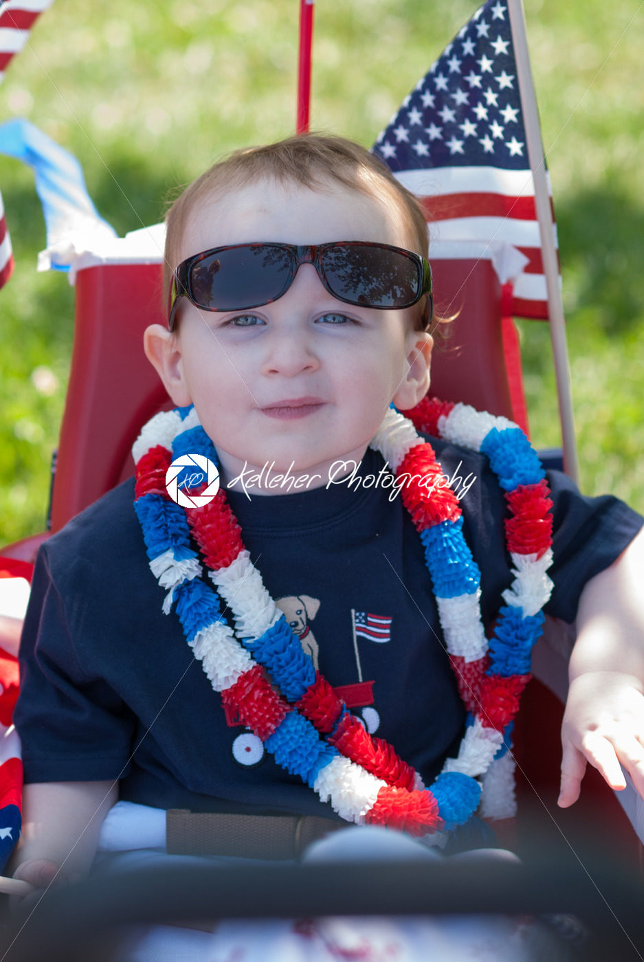 Young boy riding in red wagon having fun in the park for July Fourth - Kelleher Photography Store