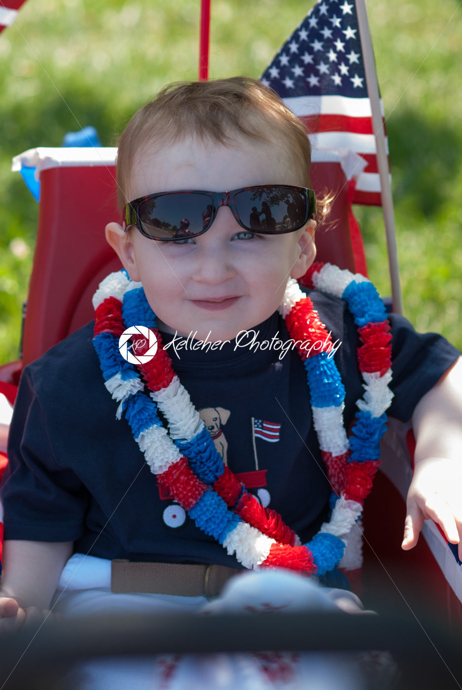 Young boy riding in red wagon having fun in the park for July Fourth - Kelleher Photography Store