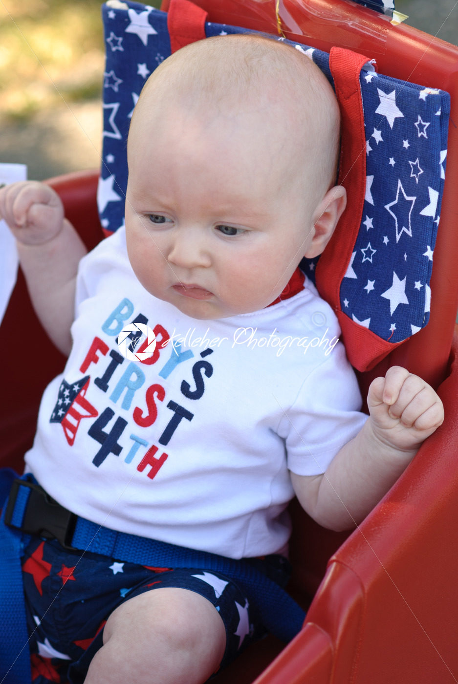 Young infant boy riding in red wagon having fun in the park for July Fourth - Kelleher Photography Store