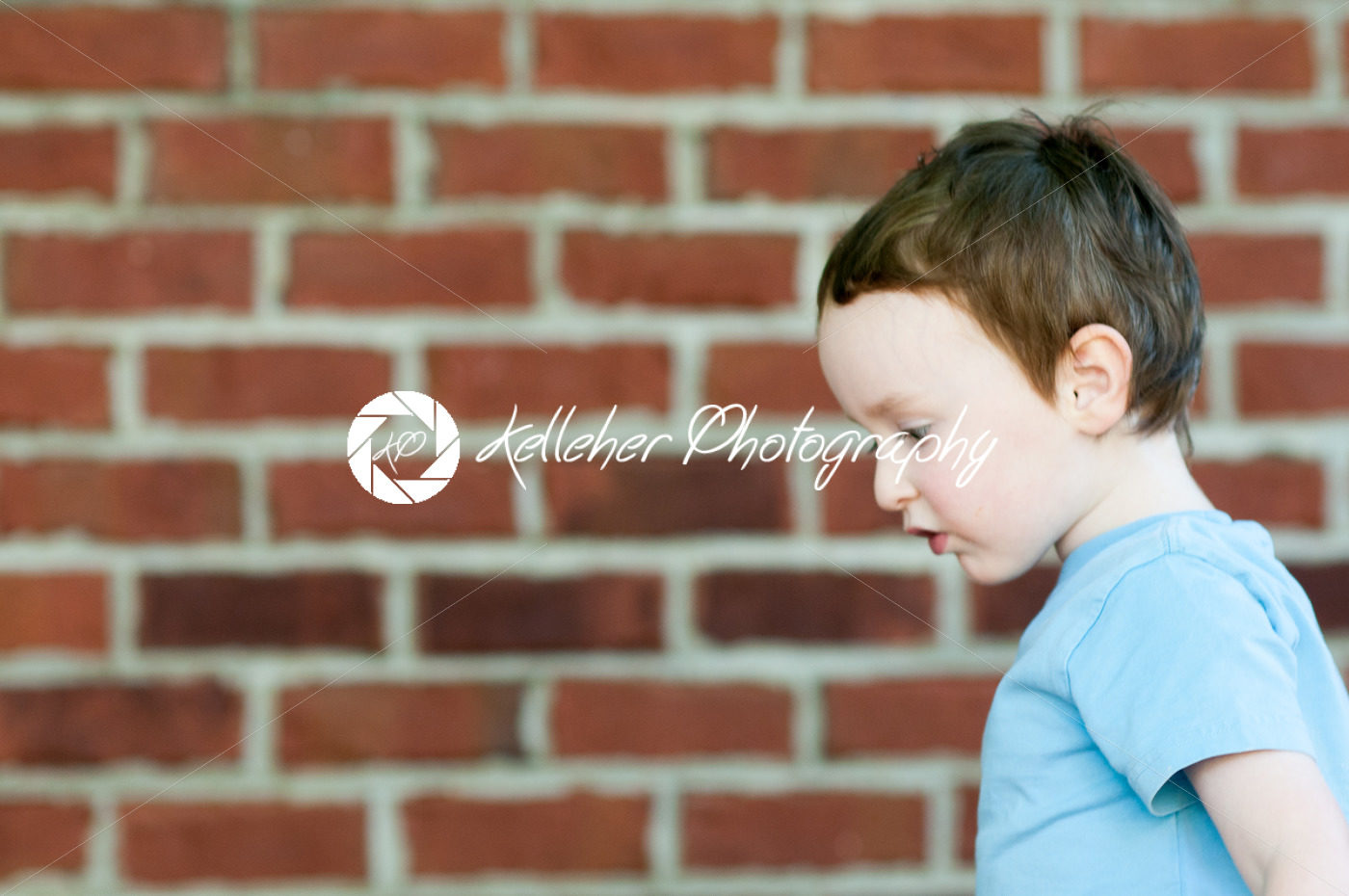 Young toddler boy in front of red birck wall - Kelleher Photography Store