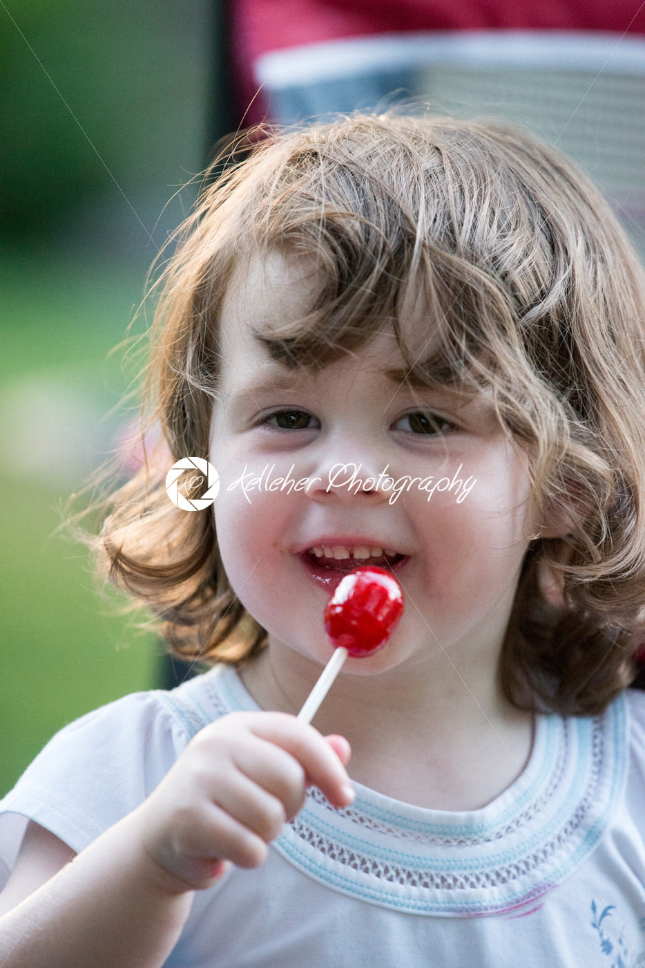 Cute little girl outside with big red lollipop. - Kelleher Photography Store