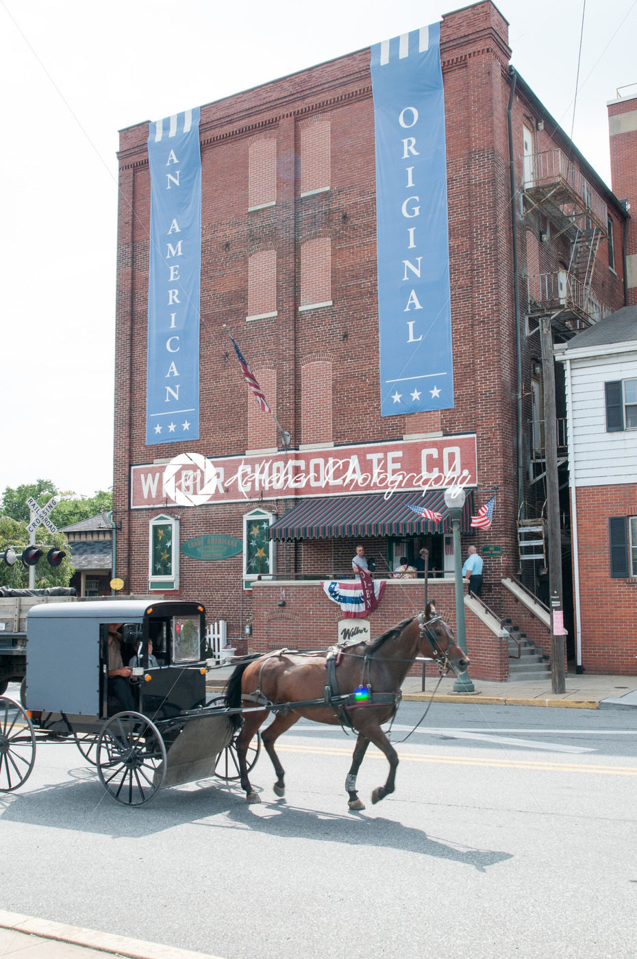 LITITZ, PA – AUGUST 30: Amish horse and buggy riding past the famed Wilbur Chocolate Company headquarters on Route 501 in Lititz on August 30, 2014 - Kelleher Photography Store