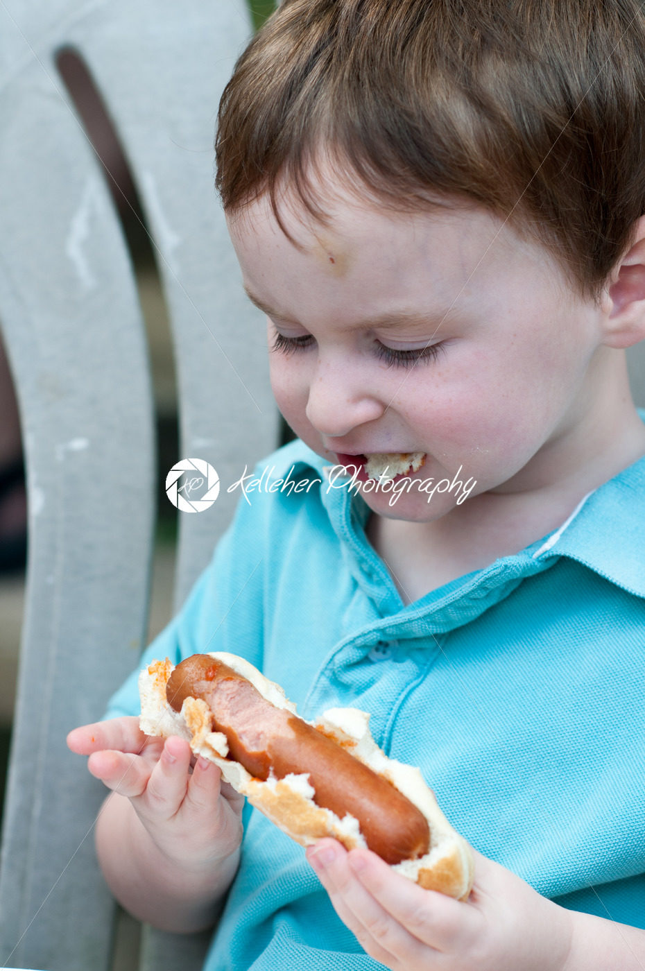 Young boy outside eating a big hot dog - Kelleher Photography Store