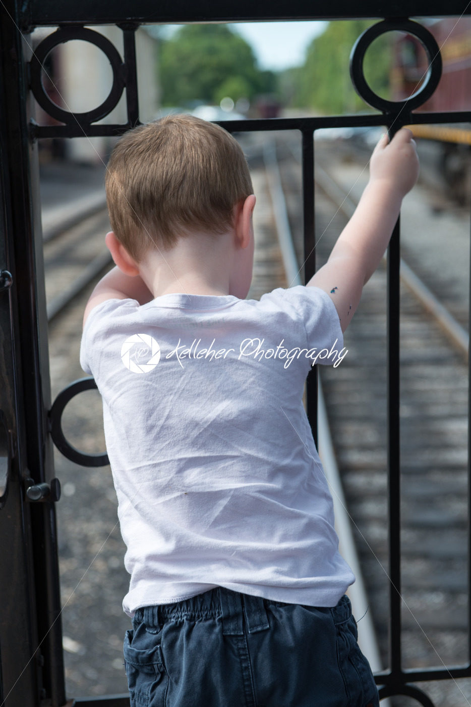 Young boy standing at back of train looking down at track - Kelleher Photography Store