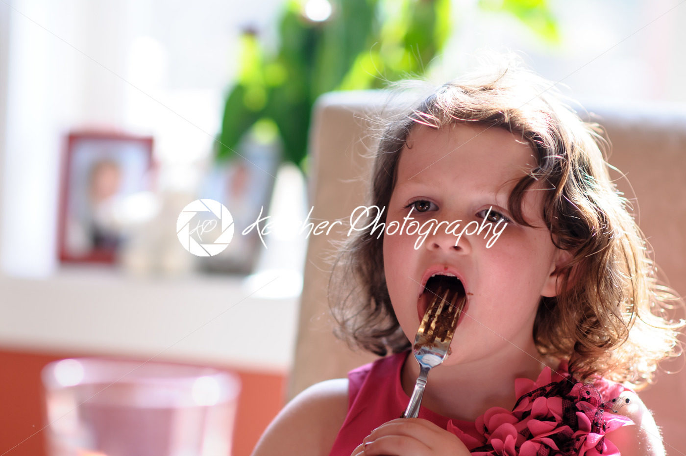 Young girl indoors eating birthday cake licking fork - Kelleher Photography Store
