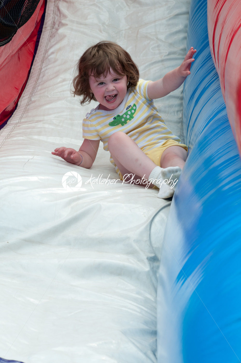 Young happy girl child riding inflatable slide outdoors on a warm summer day. - Kelleher Photography Store