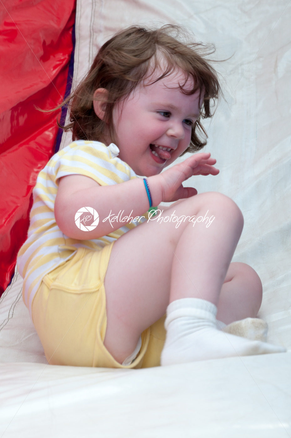 Young happy girl child riding inflatable slide outdoors on a warm summer day. - Kelleher Photography Store