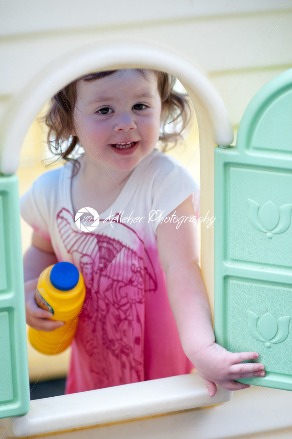 Young little girl playing in toy house in backyard on a sunny day - Kelleher Photography Store