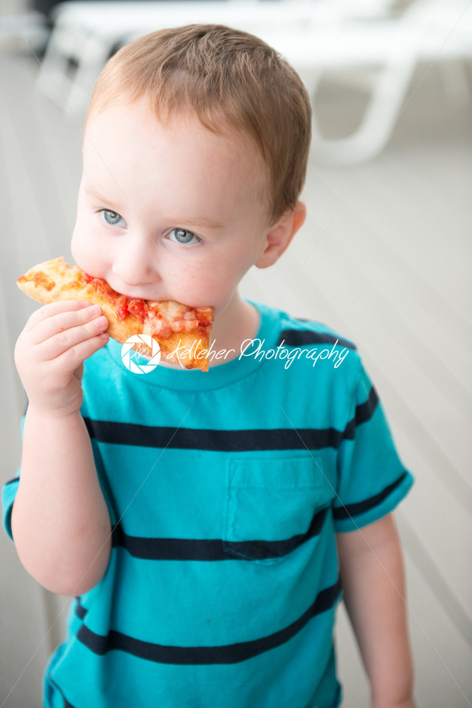 Young toddler boy on patio deck outside at sunset down at shore eating pizza - Kelleher Photography Store