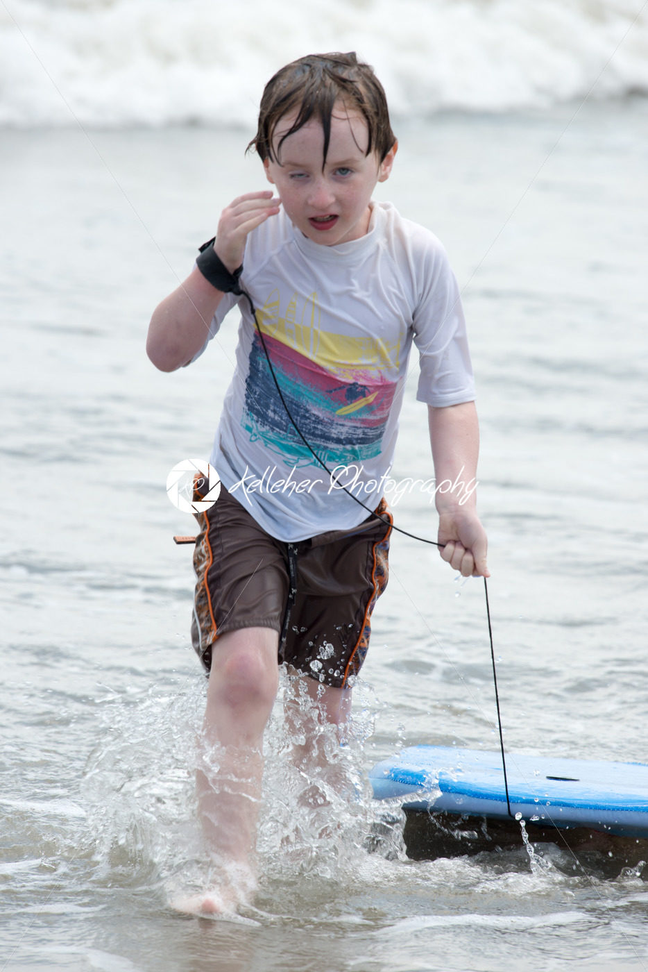 Boy coming out of the ocean waves with a boogy board - Kelleher Photography Store