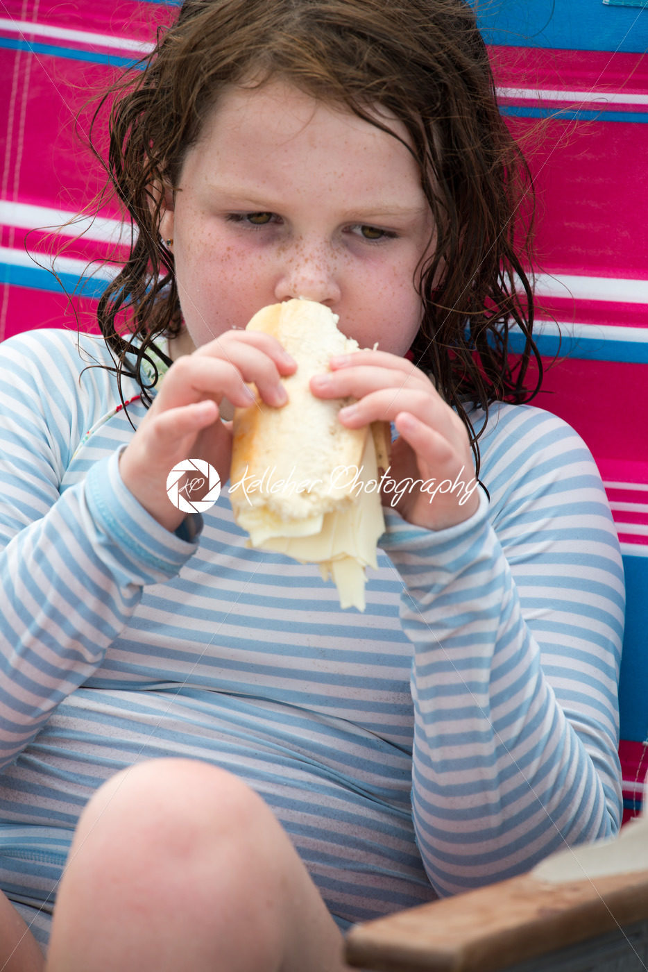 Child girl with cheese hoagie sandwhich on a deck chair by the ocean - Kelleher Photography Store