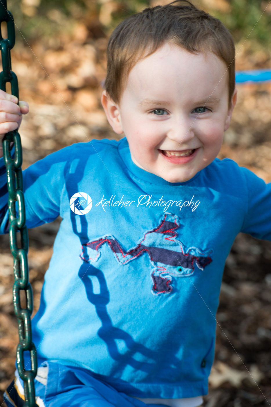 Young boy having fun outside at park on a playground swing set - Kelleher Photography Store
