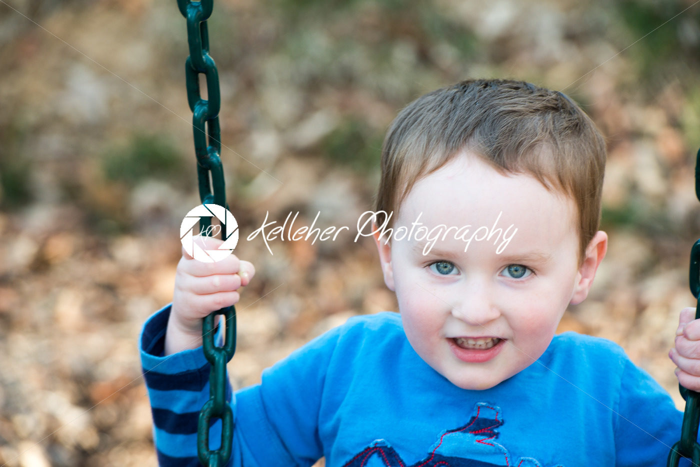 Young boy having fun outside at park on a playground swing set - Kelleher Photography Store