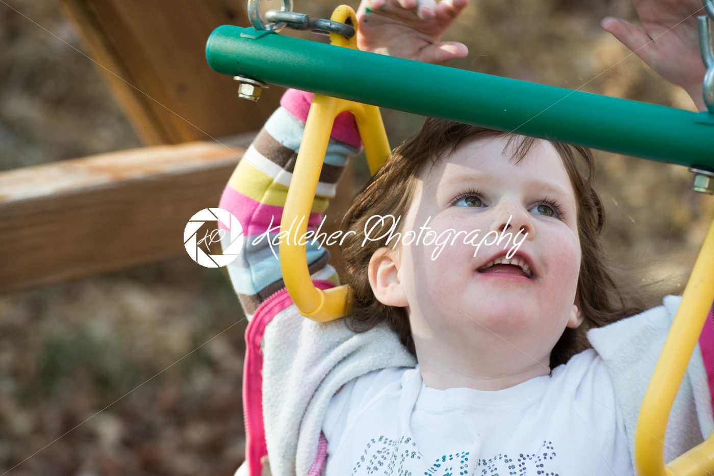 Young girl having fun outside at park on a playground swing set - Kelleher Photography Store