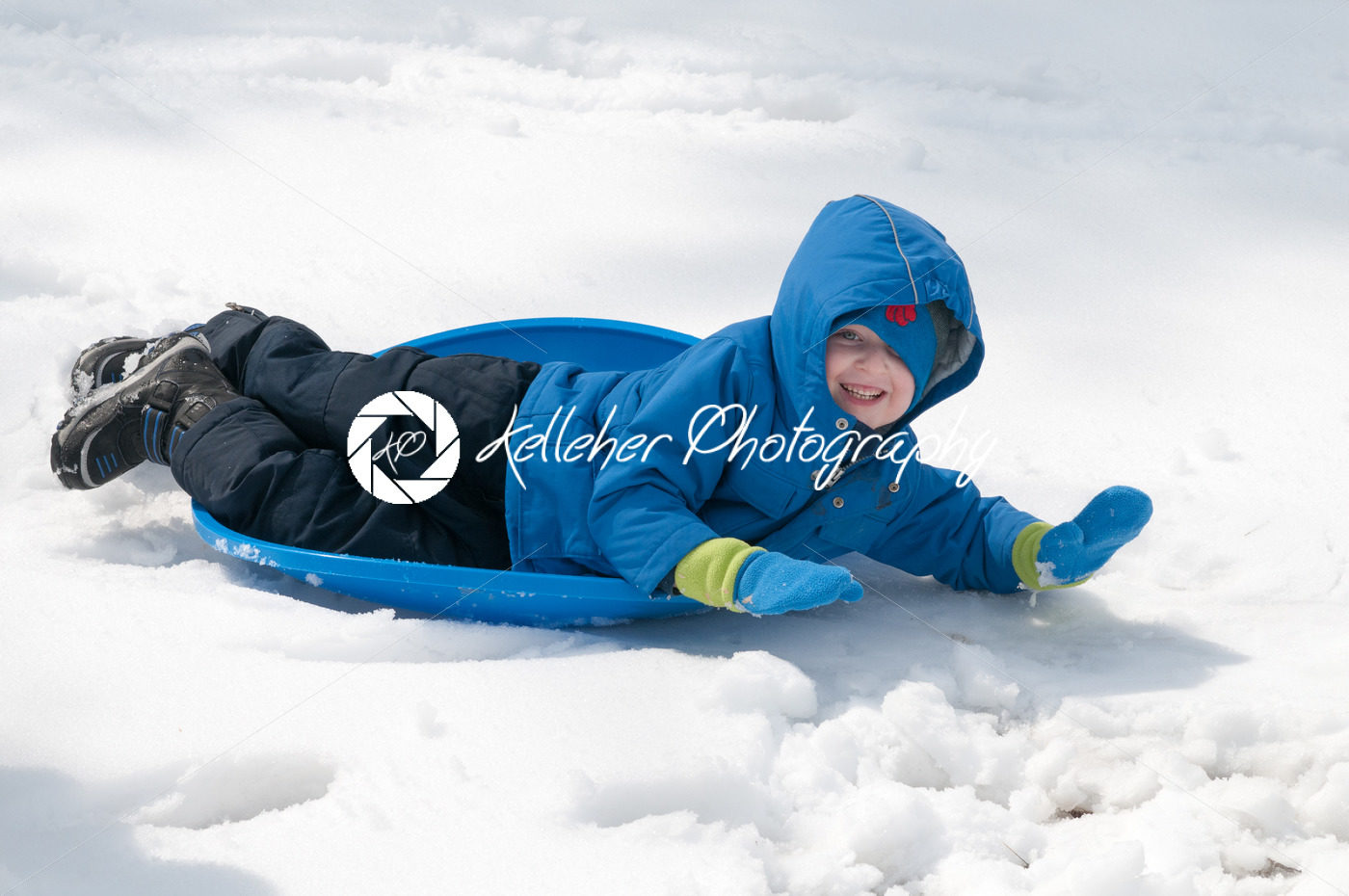 Young little boy enjoying sledding outside on a snow day - Kelleher Photography Store