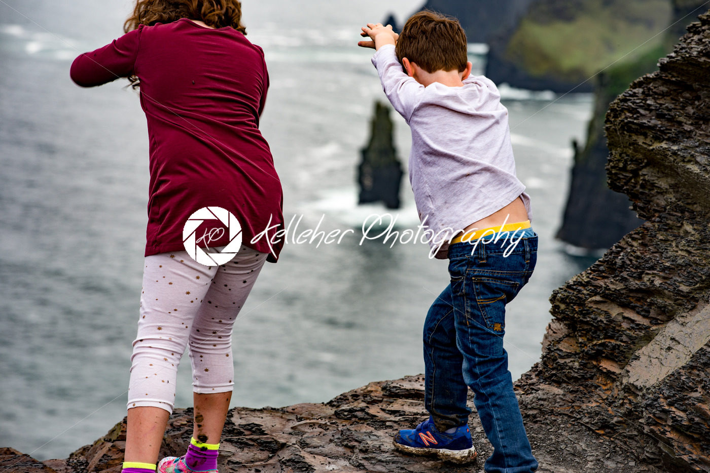 Girl and Boy pretending to dive off the Cliffs of Moher Tourist Attraction in Ireland - Kelleher Photography Store