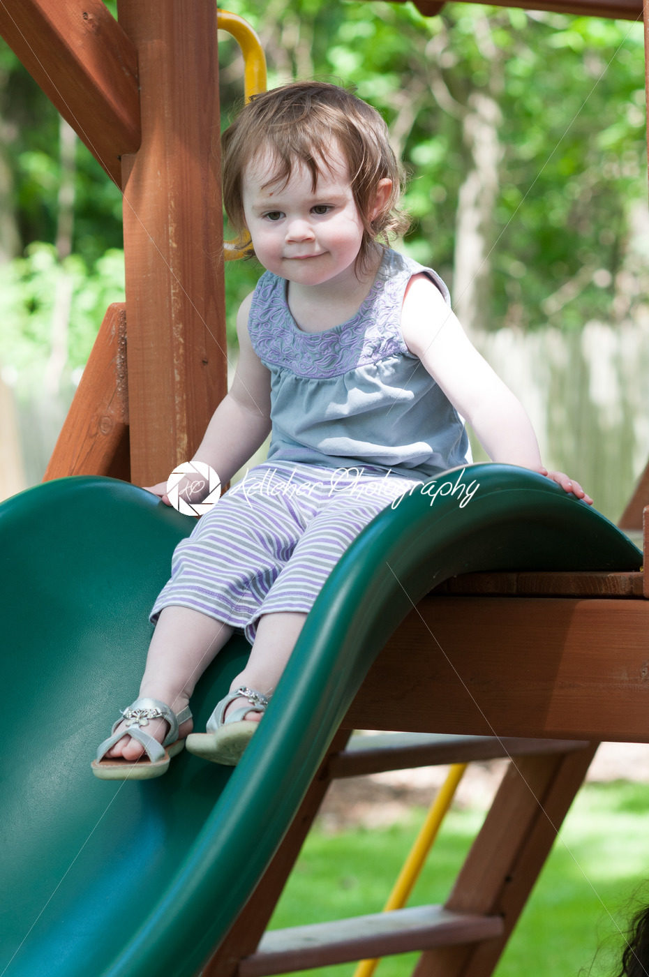 Girl riding on childrens slides on playground - Kelleher Photography Store