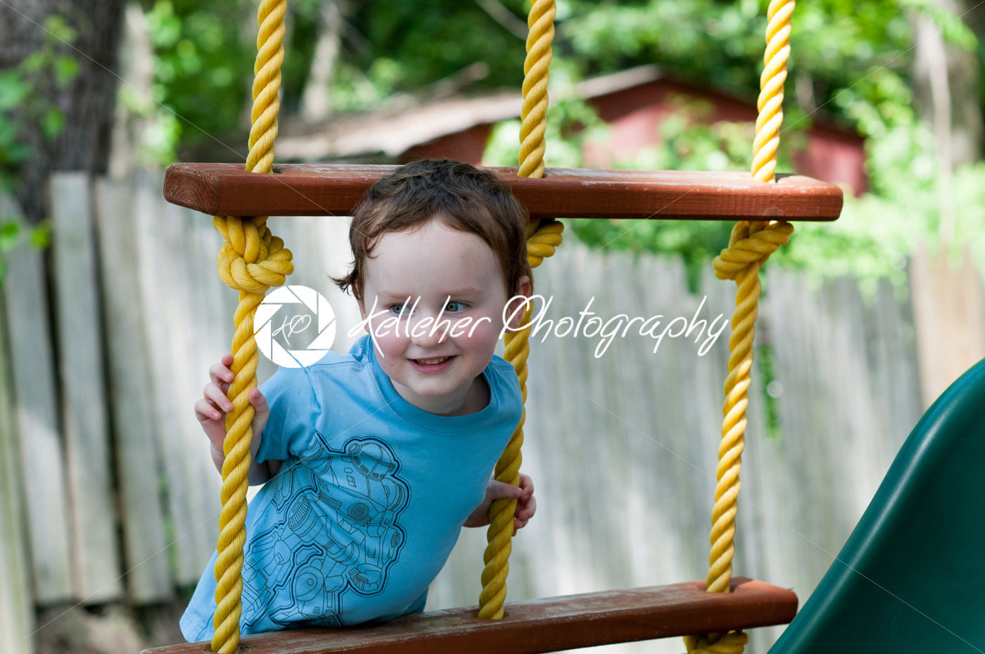 Happy little child boy climbing on the rope ladder outside - Kelleher Photography Store