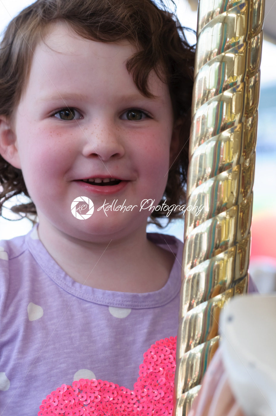 Young girl riding on fairground horse on carousel amusement ride at fairgrounds park outdoor - Kelleher Photography Store