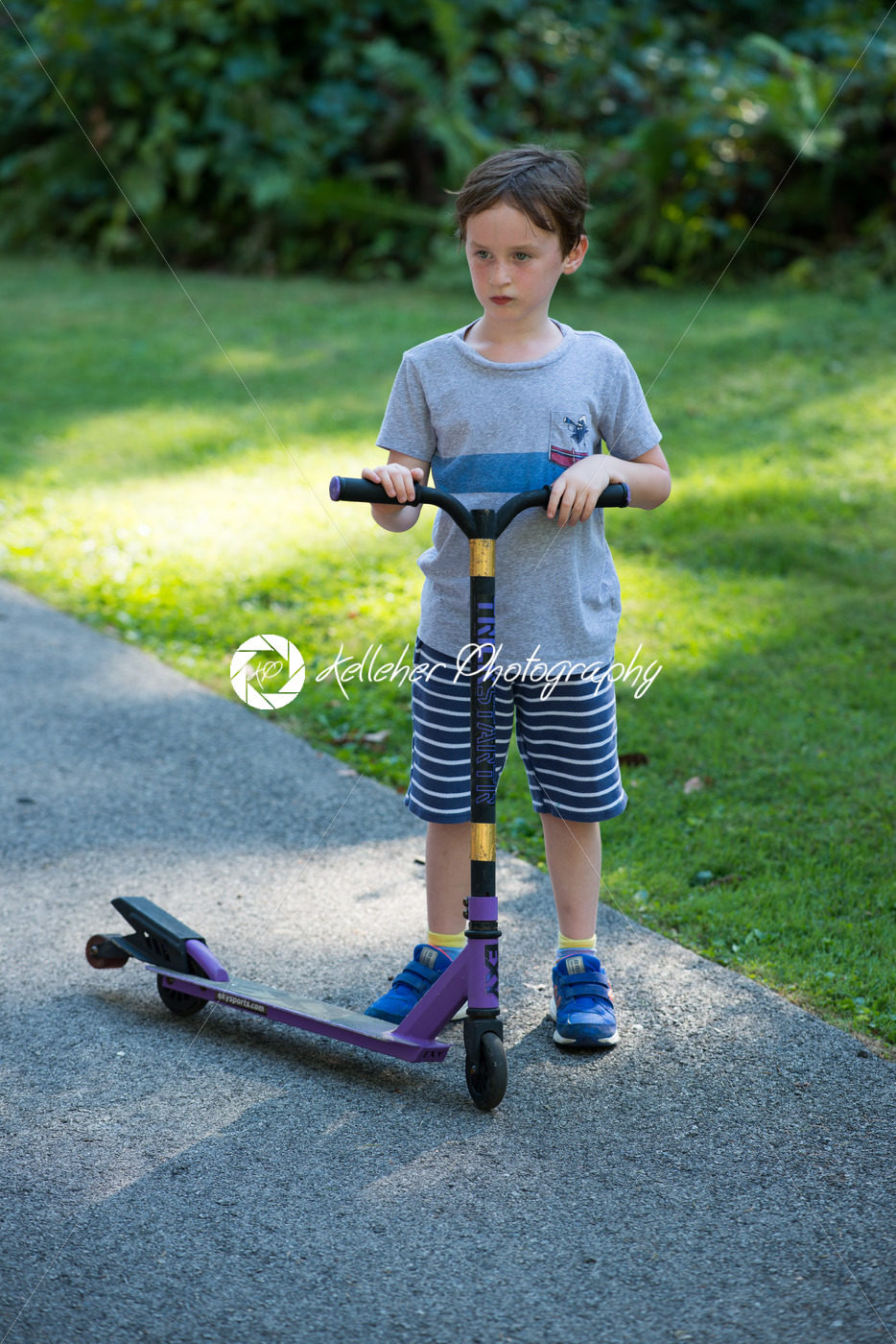 Young litte boy outside riding his scooter in the driveway - Kelleher Photography Store