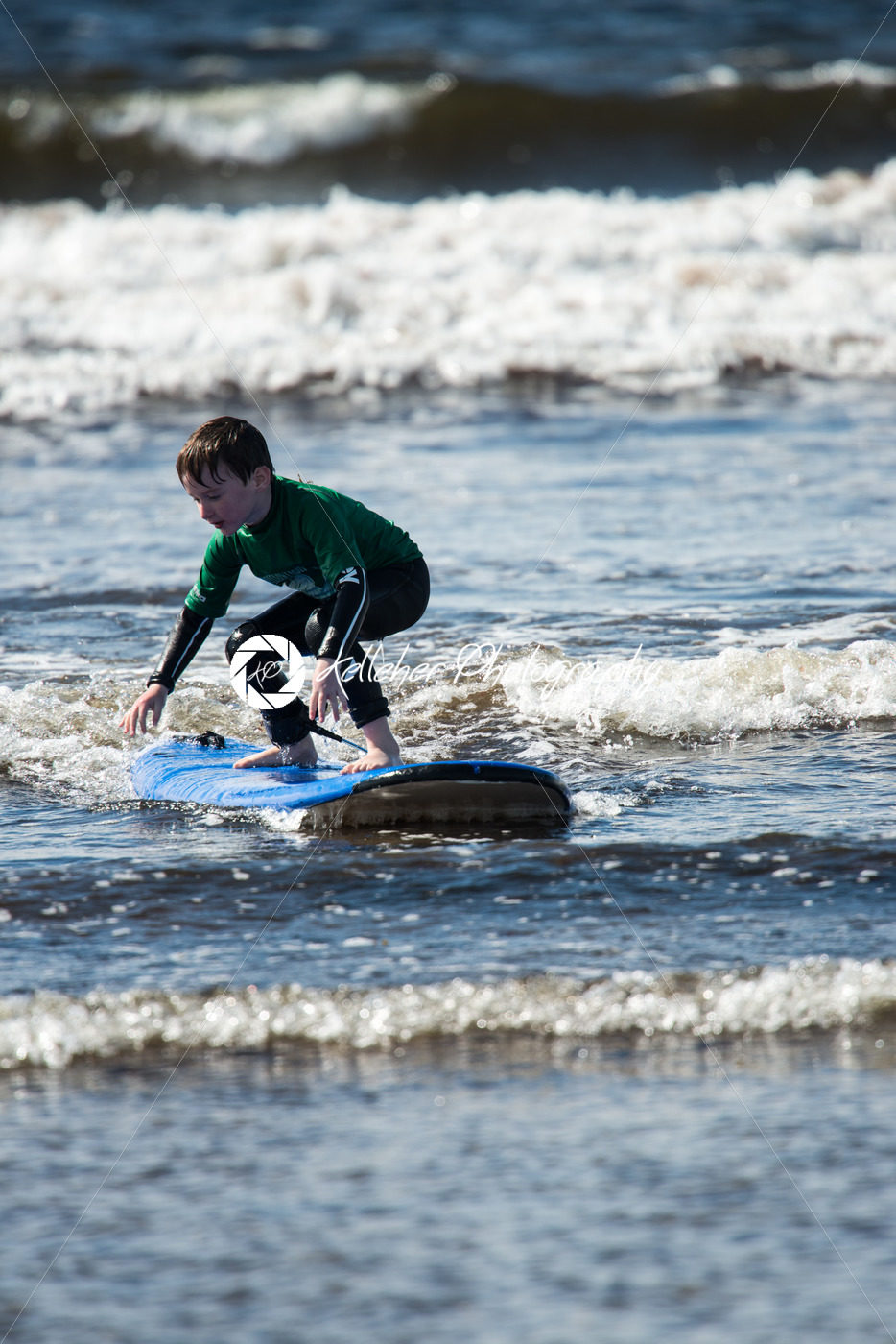 Young little boy on beach taking surfing lessons - Kelleher Photography Store