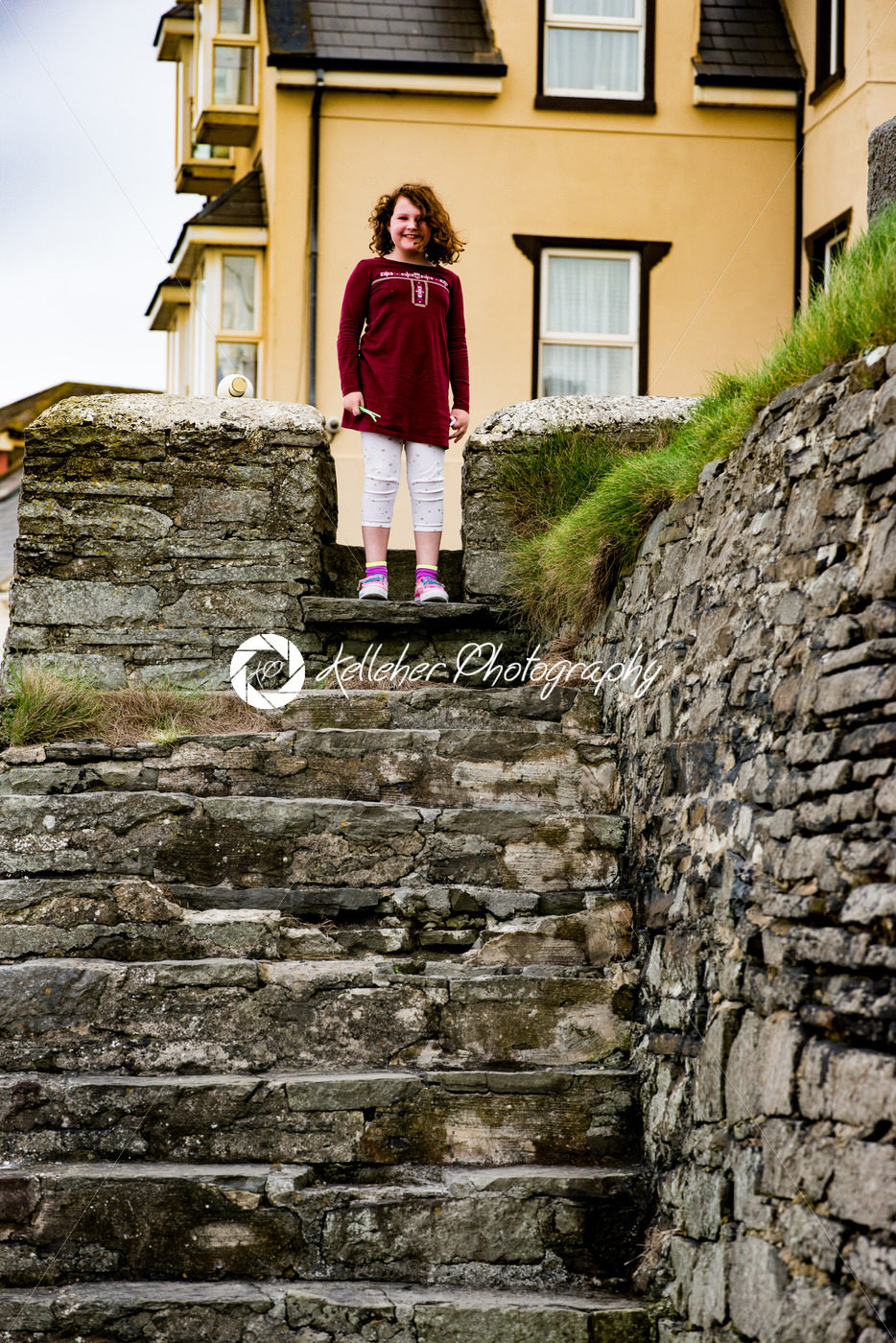 Young little girl portrait looking and smiling standing at top of rocky stairs - Kelleher Photography Store