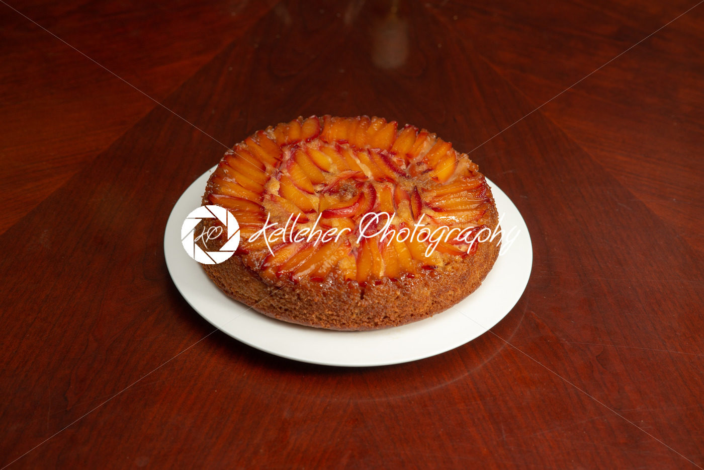 Cake with nectarines on white plate on top of dining table - Kelleher Photography Store