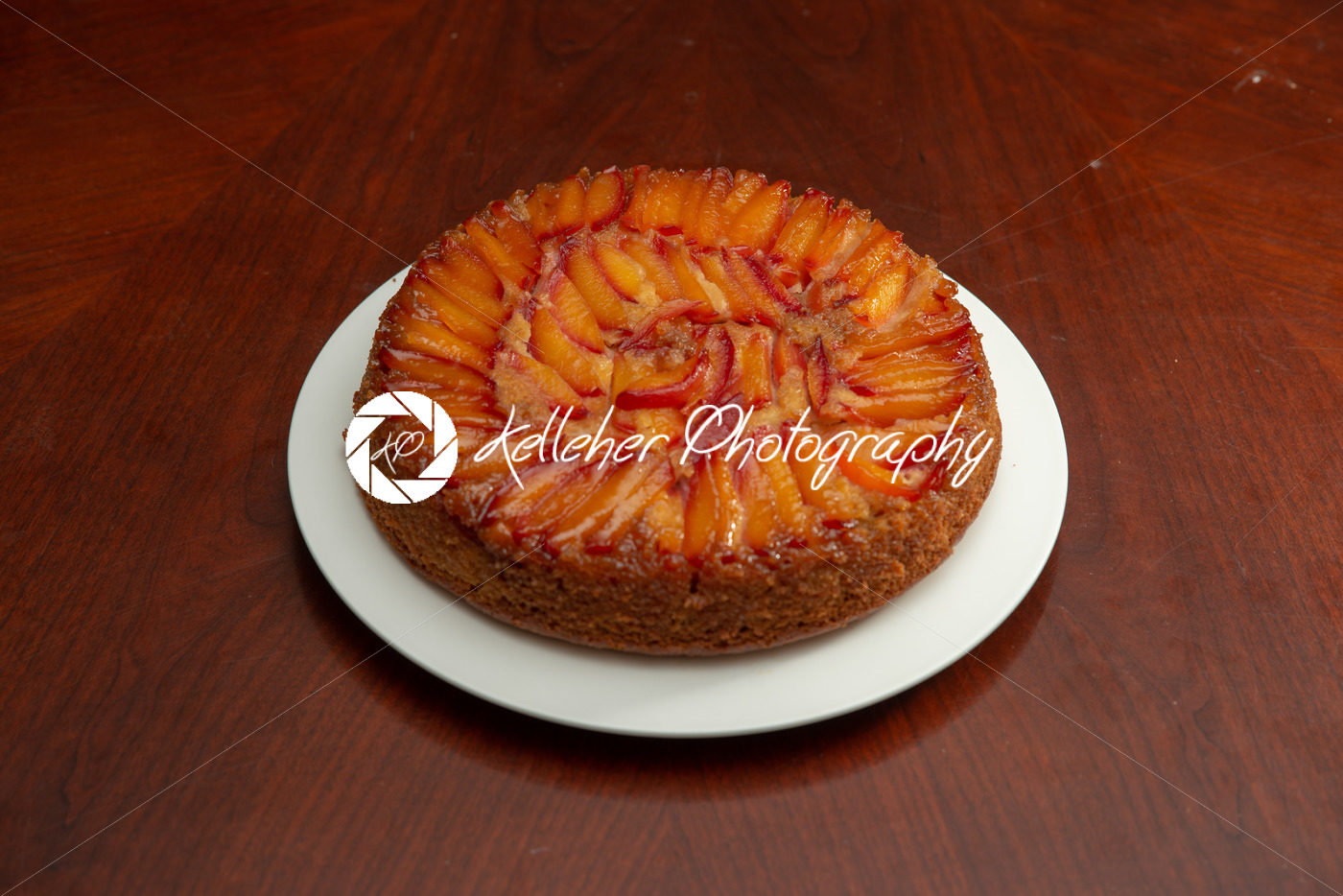 Cake with nectarines on white plate on top of dining table - Kelleher Photography Store