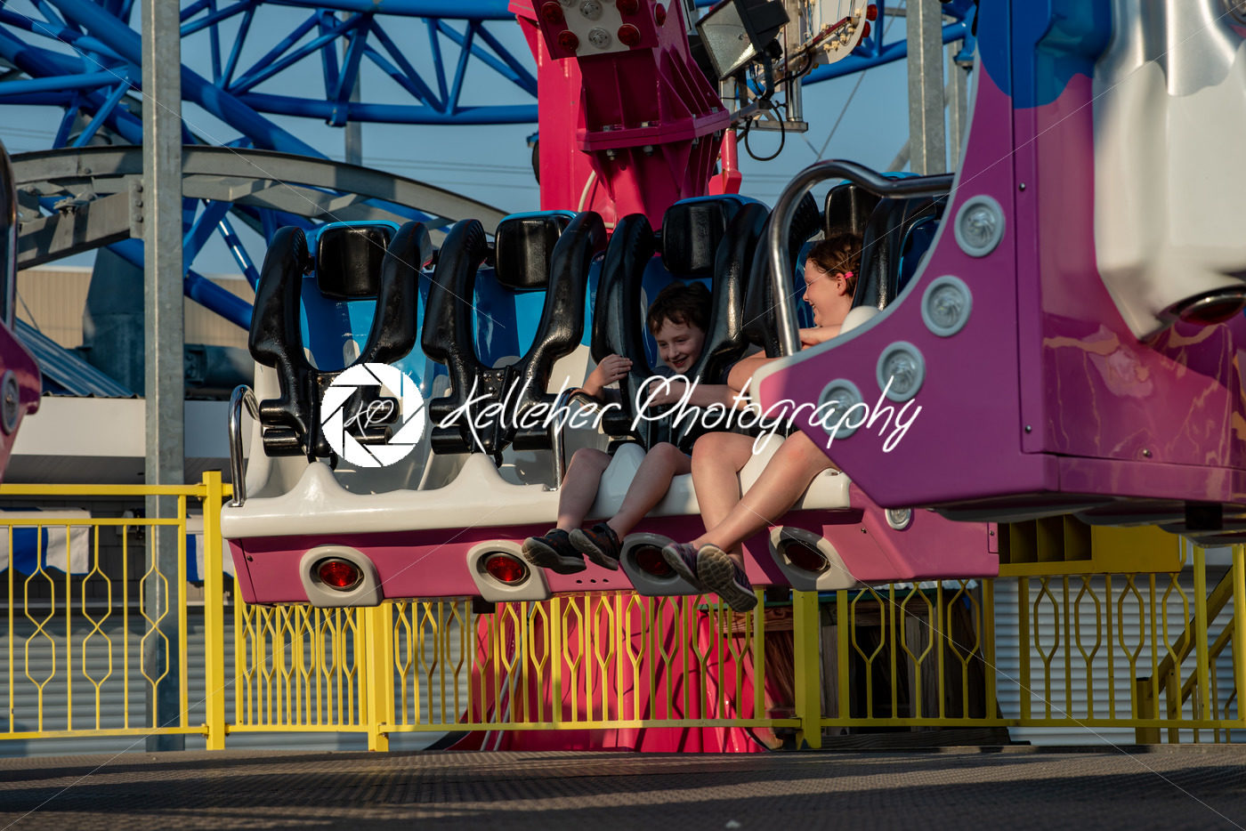 Happy young brother and sister having fun on boardwalk amusement ride - Kelleher Photography Store