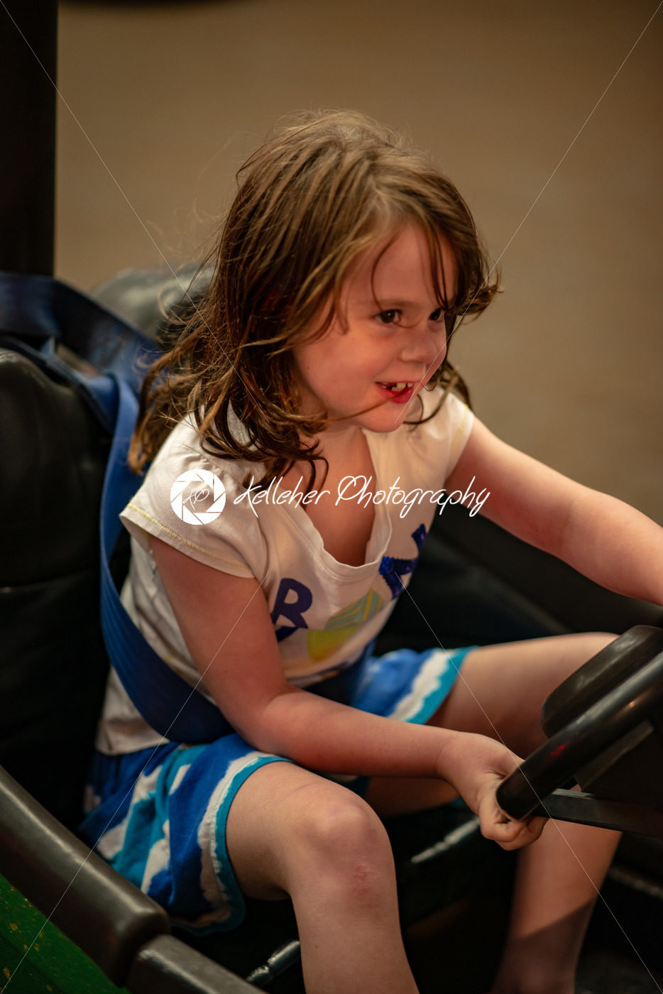 Happy young girl rides electric bumper car amusement ride on shore boardwalk - Kelleher Photography Store