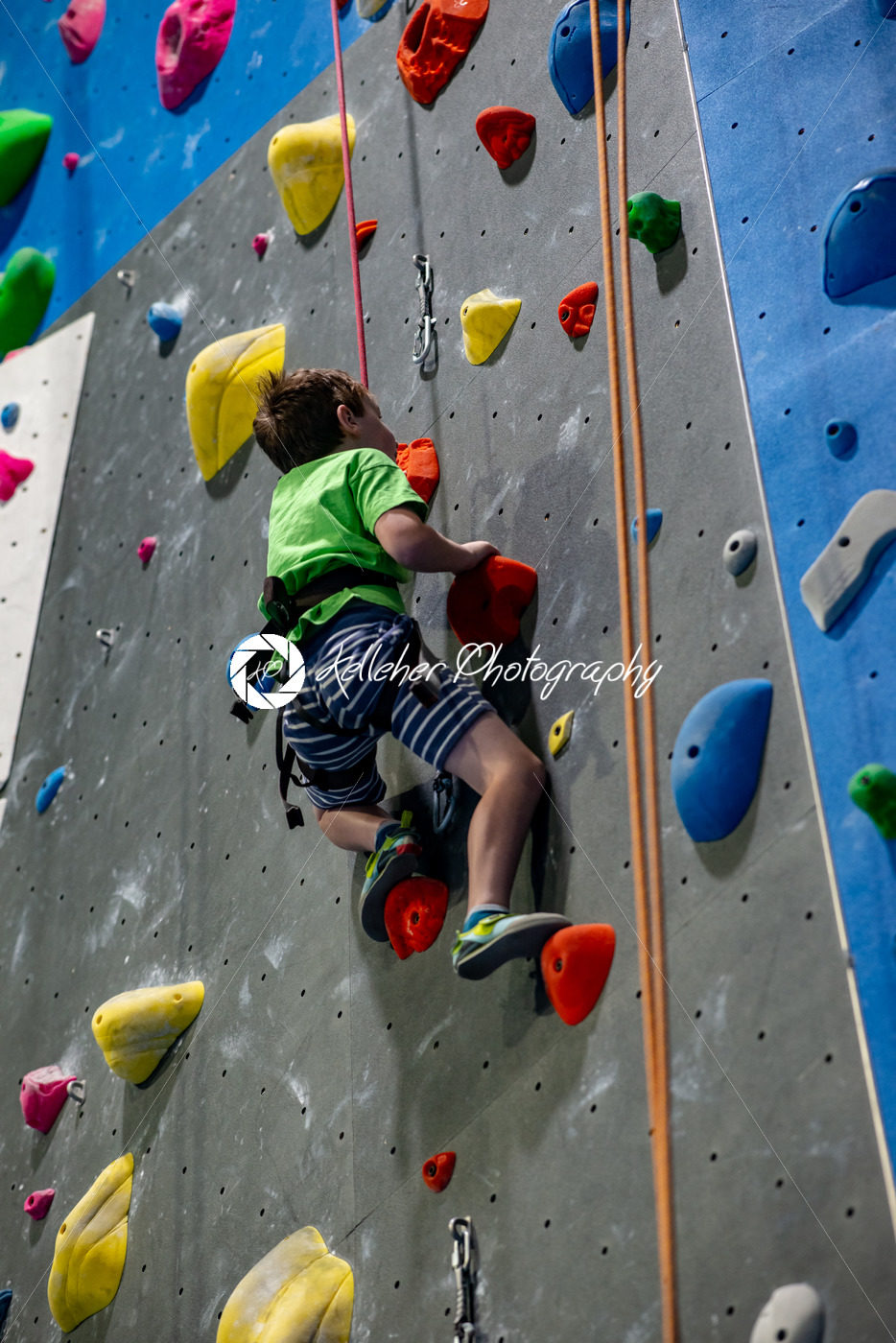 Young boy climbing up on practice wall in indoor rock gym - Kelleher Photography Store