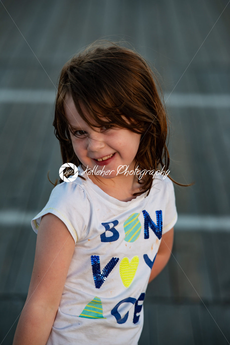 Young cute little girl on the boardwalk looking at camera smiling - Kelleher Photography Store